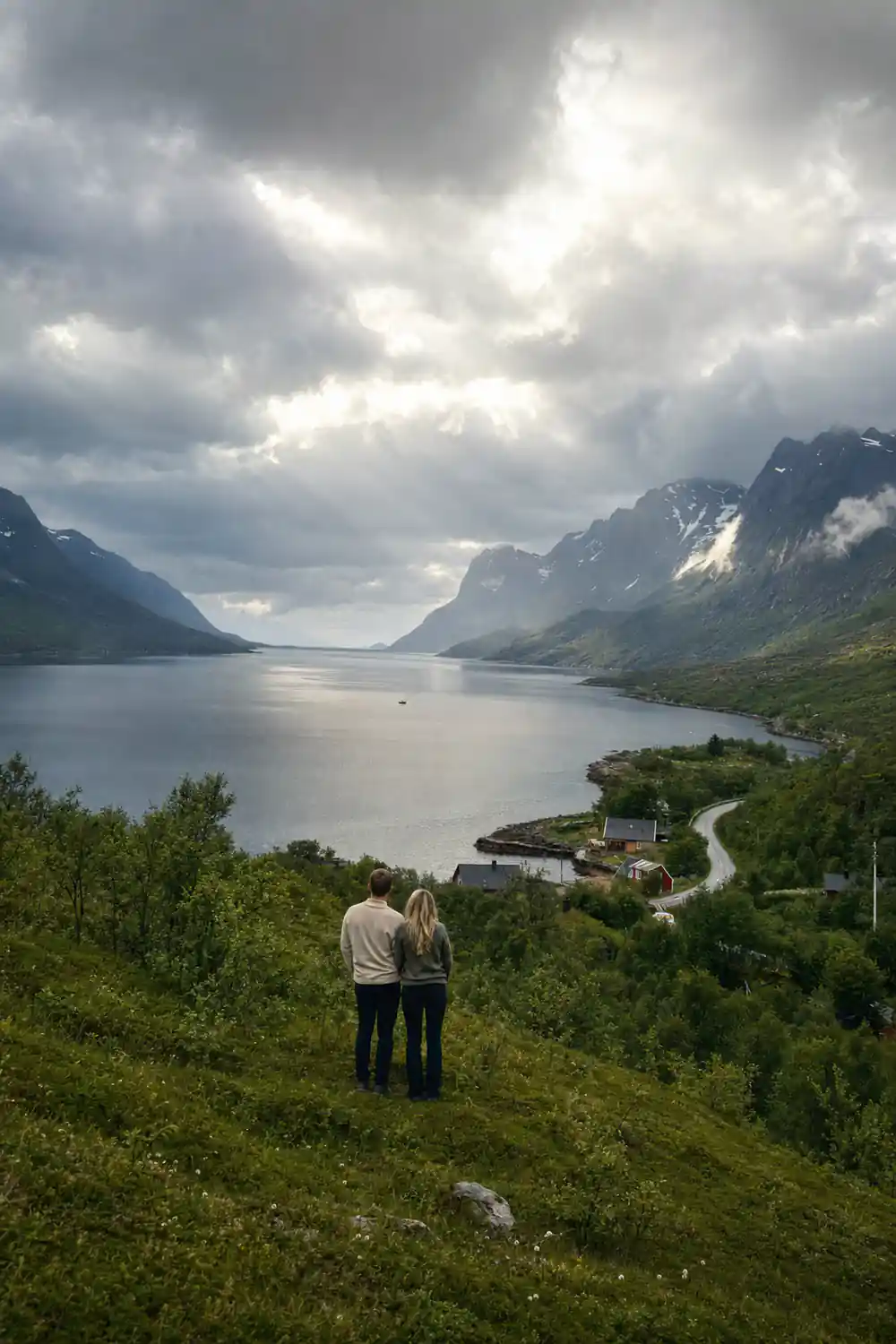 A grey fjord running between steep cloud-covered mountains