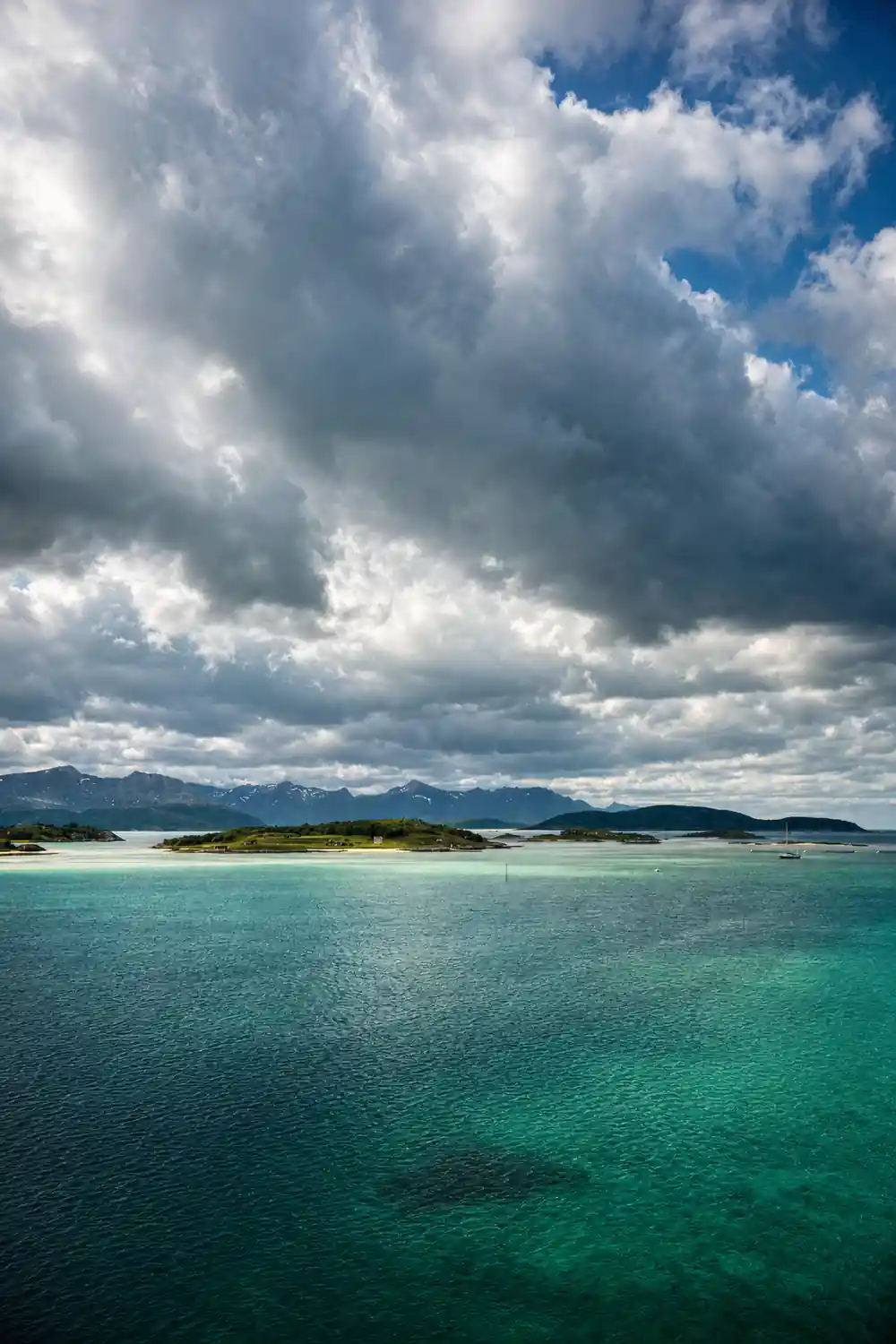 Low islands under heavy cloud across still water