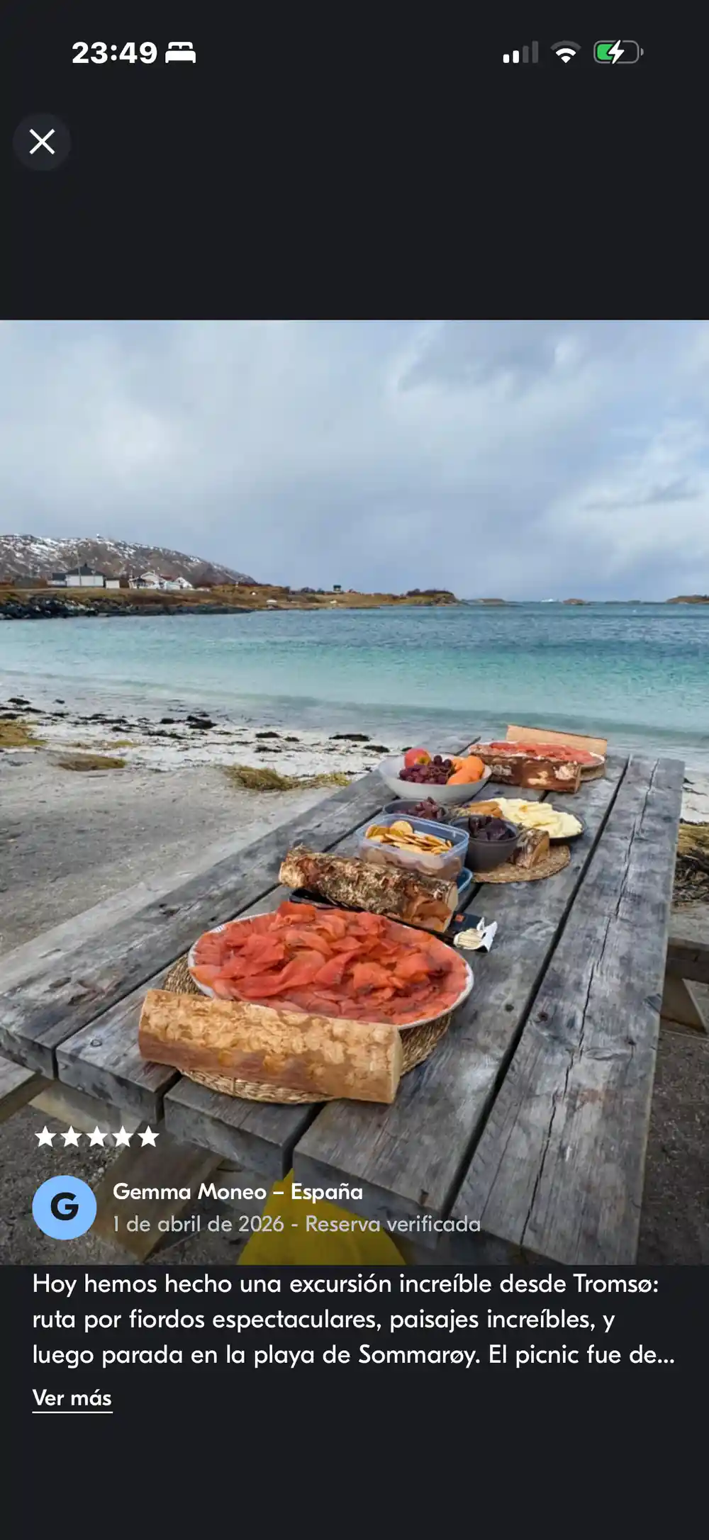 A picnic table of food on the sand with the village beyond