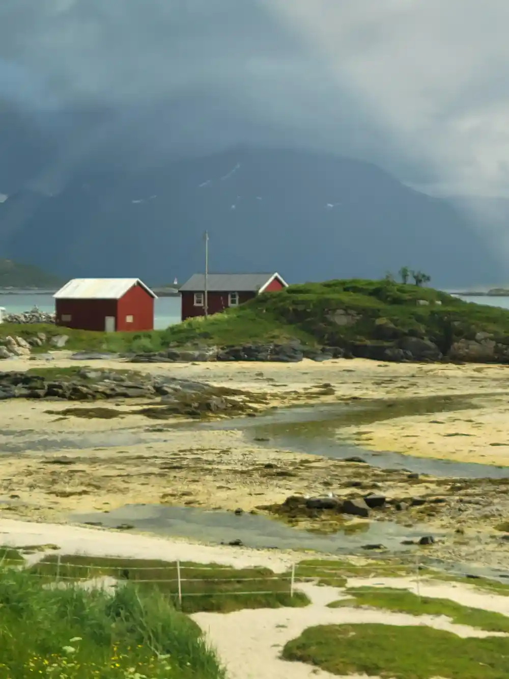 A red cabin on a low green island above the shallows