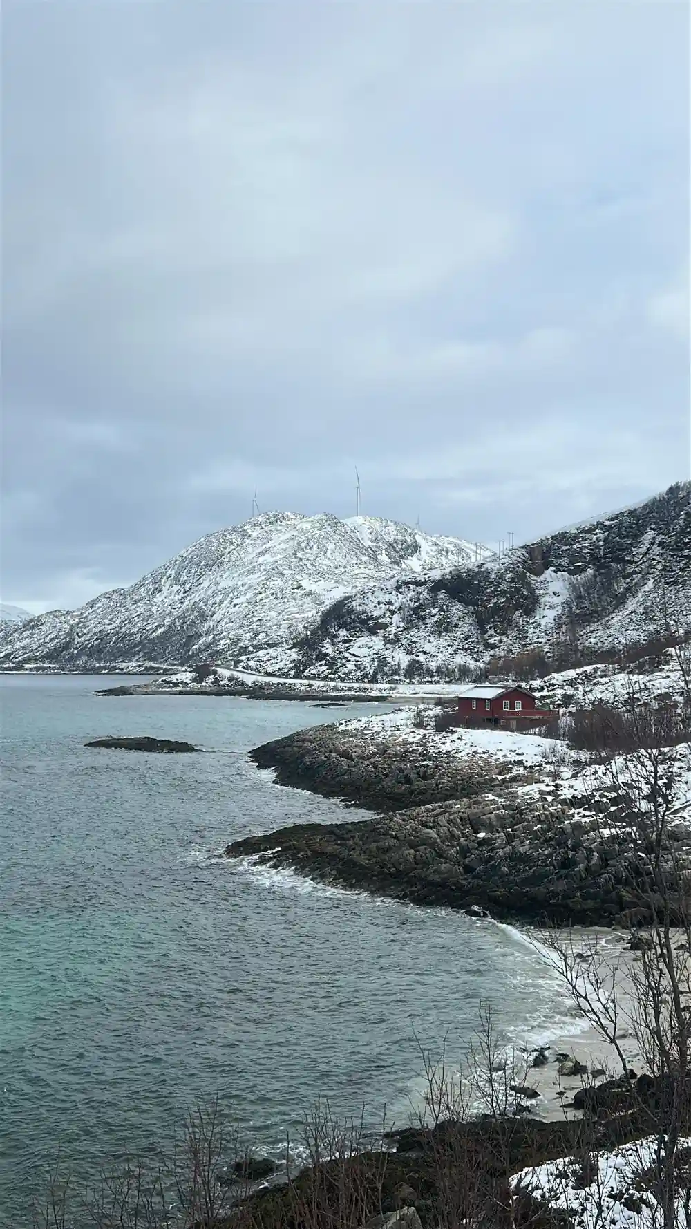 A snow-covered rocky island with a red cabin on it
