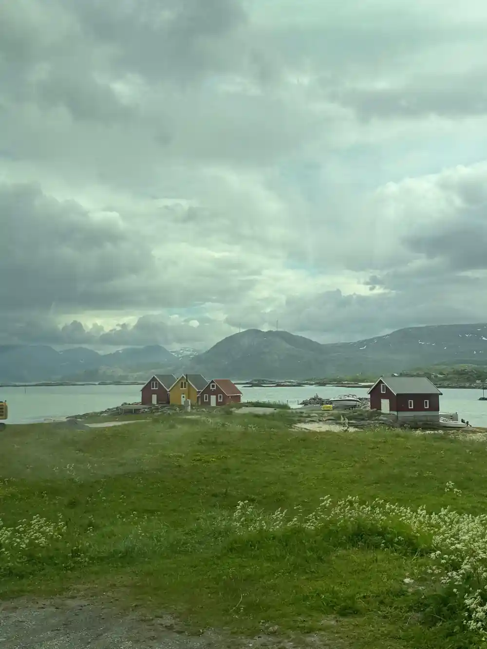 Timber cabins on green grass under a heavy sky